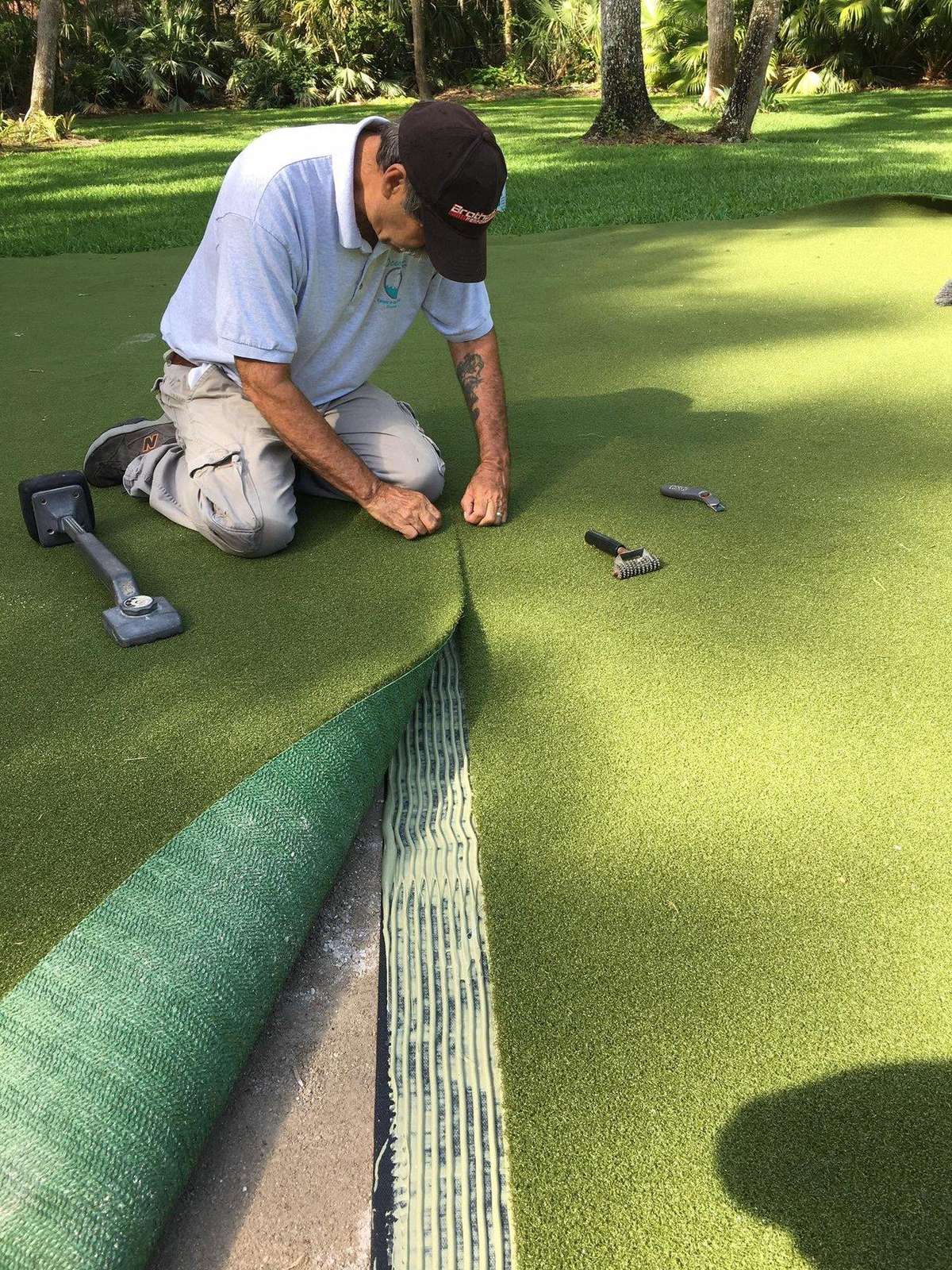 Shane hand-seaming a fresh astroturf installation