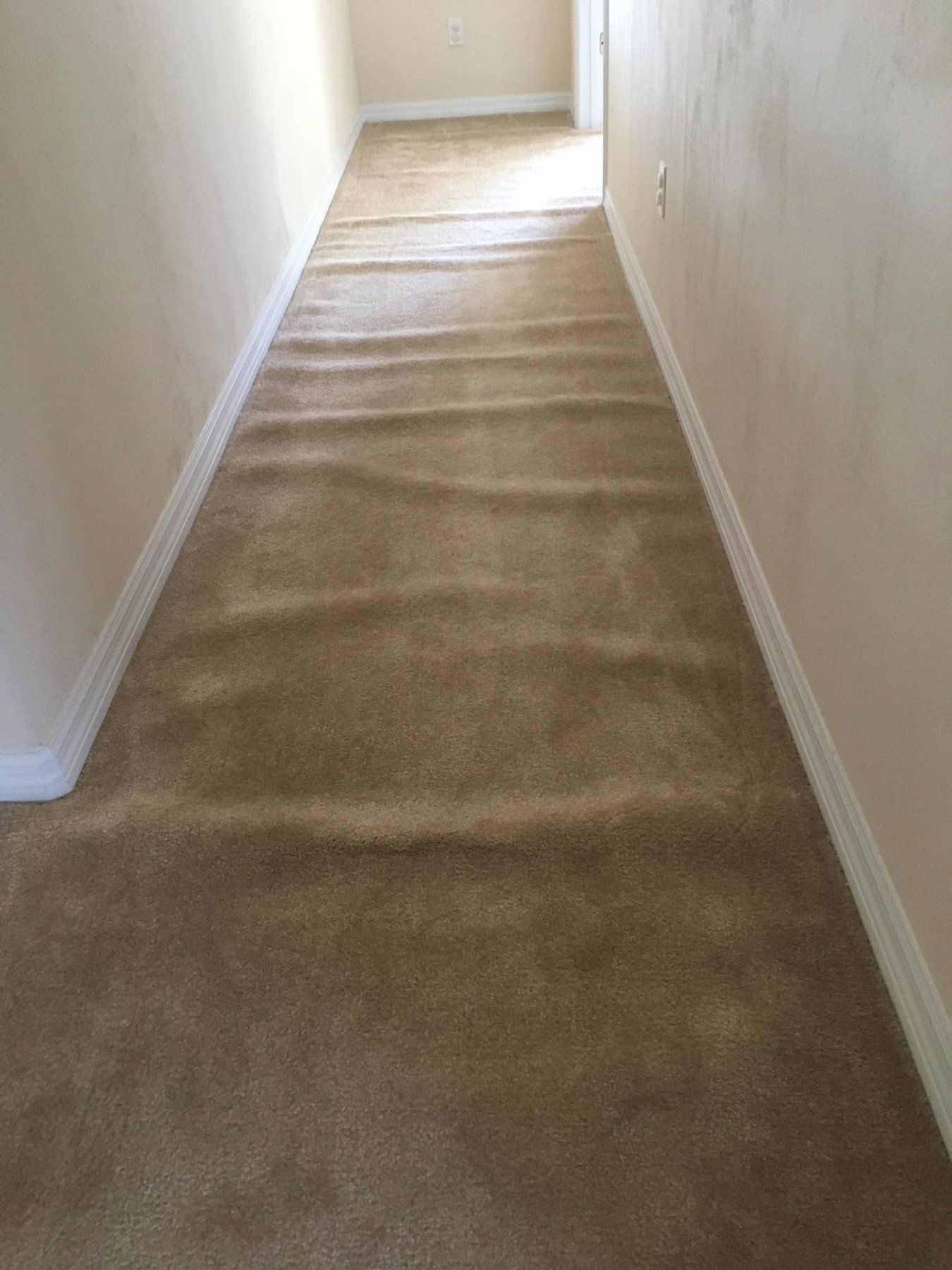 Rippled, wavy hallway carpet before re-stretching