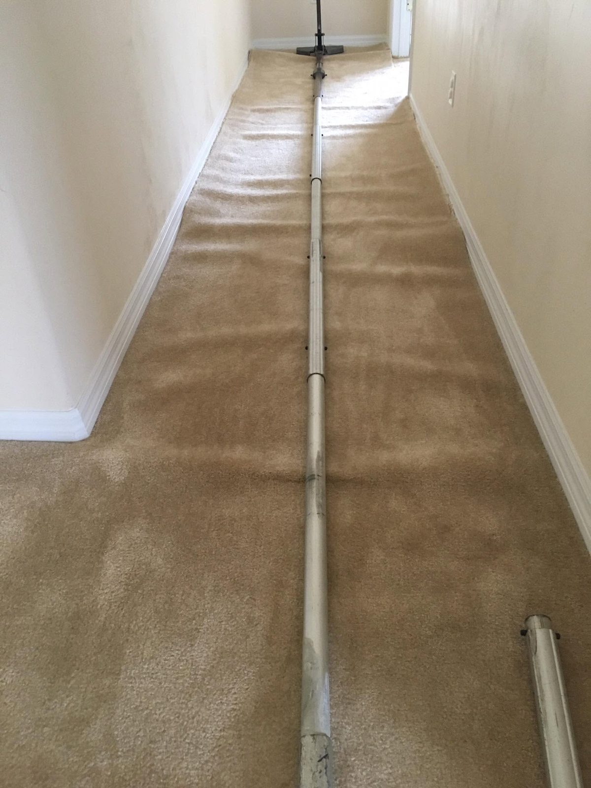Carpet stretching tool spanning a hallway